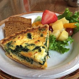 a slice of quiche and fruit salad