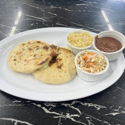 Two delicious Papusas with a side of curtido, rice, and beans