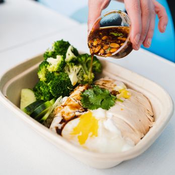 Rooster & Rice - a person pouring sauce over a bowl of food - Comfort Food Near Me - Beaverton, Oregon Rooster & Rice - a person pouring sauce over a bowl of food - Comfort Food Near Me - Beaverton, Oregon