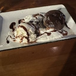 Sad looking flourless chocolate cake with a puddle of whipped cream and vanilla ice cream.