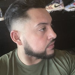 Low skin fade with comb back hair cut and beard.