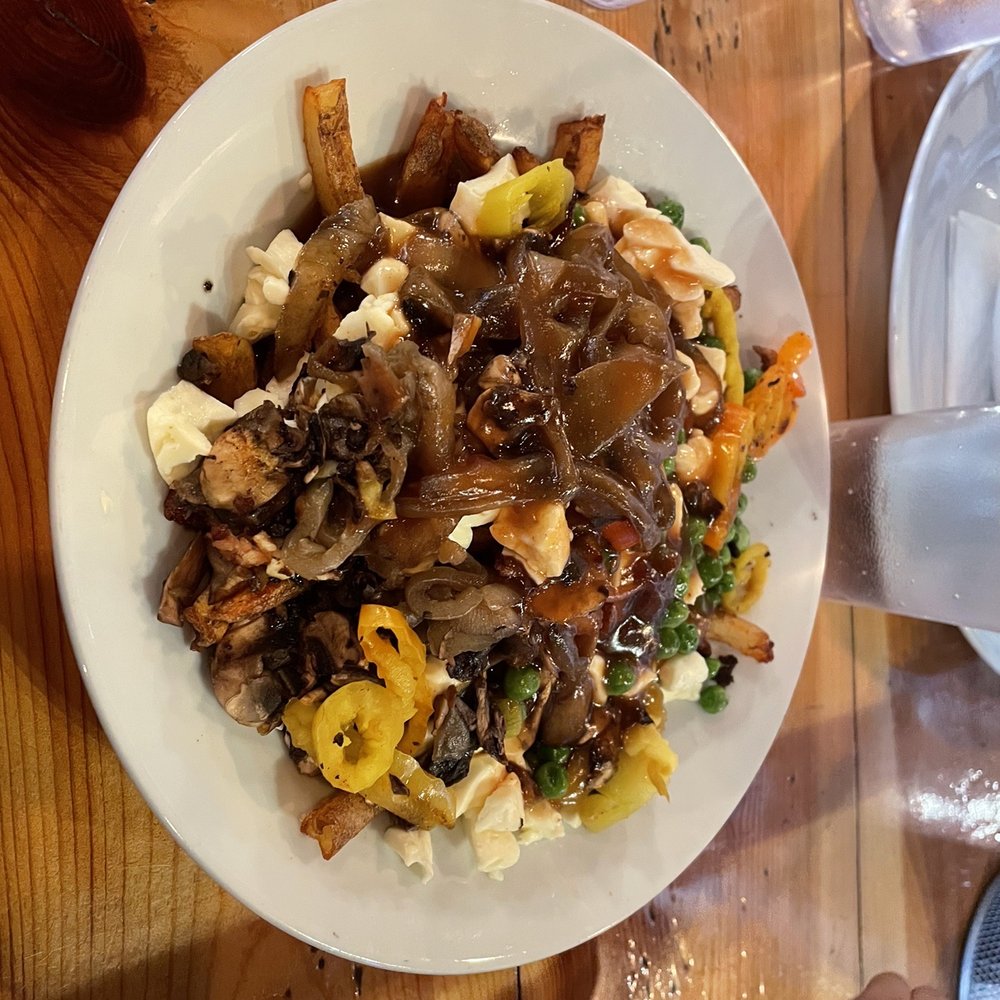 Poutineville - a plate of food on a wooden table - Poutineries Near Me - Montreal, Quebec