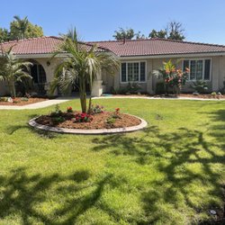 La Casita Residential Care - A landscaped outdoor area at La Casita Residential Care with an open lawn, flowers, and shaded residential surroundings.