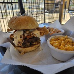Chicken Fried Bacon - A fried chicken sandwich with cheese curds and macaroni and cheese served outdoors at a restaurant.