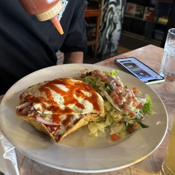 Sneaky Dee's - Adding the hot sauce to huevos rancheros - Tex-Mex Near Me - Toronto, Ontario