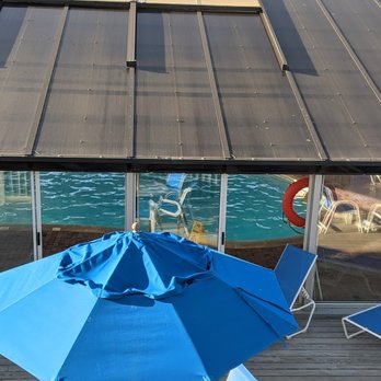 Montauk Blue Hotel - View from outside the pool. There are tables and umbrellas set up outside the pool area . - Hotels Near Me - Montauk, New York Montauk Blue Hotel - View from outside the pool. There are tables and umbrellas set up outside the pool area . - Hotels Near Me - Montauk, New York