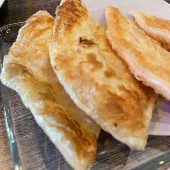 Paste Thai - Roti - Fried dumplings are arranged on a glass plate with a paper liner, placed on a wooden table, showing a golden-brown crispy exterior. - Thai Near Me - Davis, California