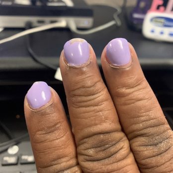 Paradise Nails - Broken chipped dipped nails after 1 week - The image depicts three fingers with lavender-colored nail polish, which is chipped at the edges. The skin around the nails appears dry and slightly cracked. The background shows a computer desk with a keyboard, cables, and various office supplies, indicating an indoor workspace setting. - Nail Salons Near Me - Madison, Wisconsin