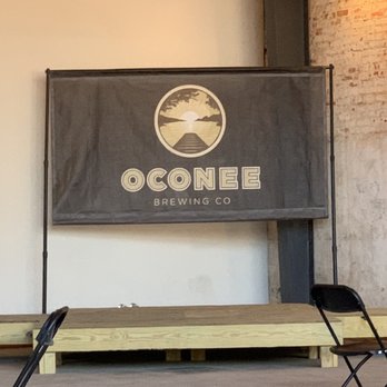 Oconee Brewing - tables and chairs in front of a sign - Breweries Near Me - Greensboro, Georgia Oconee Brewing - tables and chairs in front of a sign - Breweries Near Me - Greensboro, Georgia