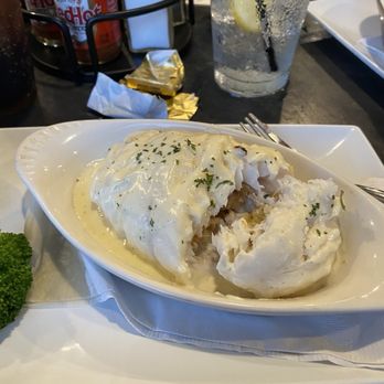 Patio 03907 - All great. - A seafood casserole with white sauce, garnished with herbs, served in a white dish on a restaurant table with drinks and condiments. - Seafood Near Me - Ogunquit, Maine