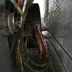 Speedy AC Duct Cleaning Service® - This close-up photo reveals a severely dust-caked bundle of electrical wires and components within an AC unit...