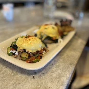 Sulmona - Charred Seasonal Eggs Benedict with red onion, tomatoes, spinach on an English muffin with hollandaise sauce and home fries! - Pizza Near Me - Cambridge, Massachusetts