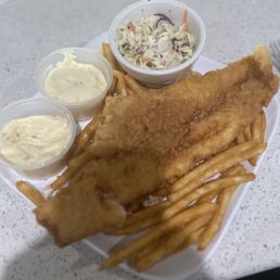 Fish/Chips mediocre at best - A serving of fried fish with French fries, coleslaw in a small bowl, and two cups of tartar sauce on a white tray.