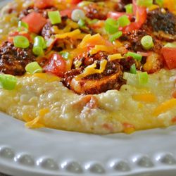 Jim's Place - A popular special, the shrimp and grits! Cheddar cheese grits topped with bacon, tomatoes, scallions, and blackened shrimp