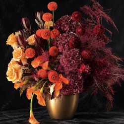 Spring Flowers & Gifts - Luxury floral arrangement with orange dahlias, apricot roses, burgundy hydrangeas and calla lilies in a champagne-gold vase by Spring Flower