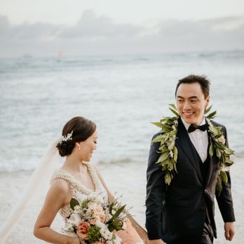 Derek Wong Photography - Bride and Groom walking on the beach in front of the Halekulani Hau Terrace - Photographers Near Me Derek Wong Photography - Bride and Groom walking on the beach in front of the Halekulani Hau Terrace - Photographers Near Me
