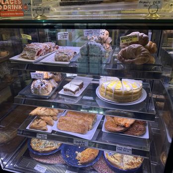 Blackbird Coffee House - A glass display case showcases an assortment of baked items including cakes, croissants, cookies, and pies, with handwritten labels and prices. - Coffee & Tea Near Me - Albuquerque, New Mexico