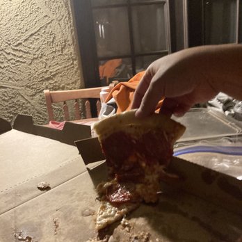 Little Caesars - a person taking a slice of pizza - Pizza Near Me - Coolidge, Arizona