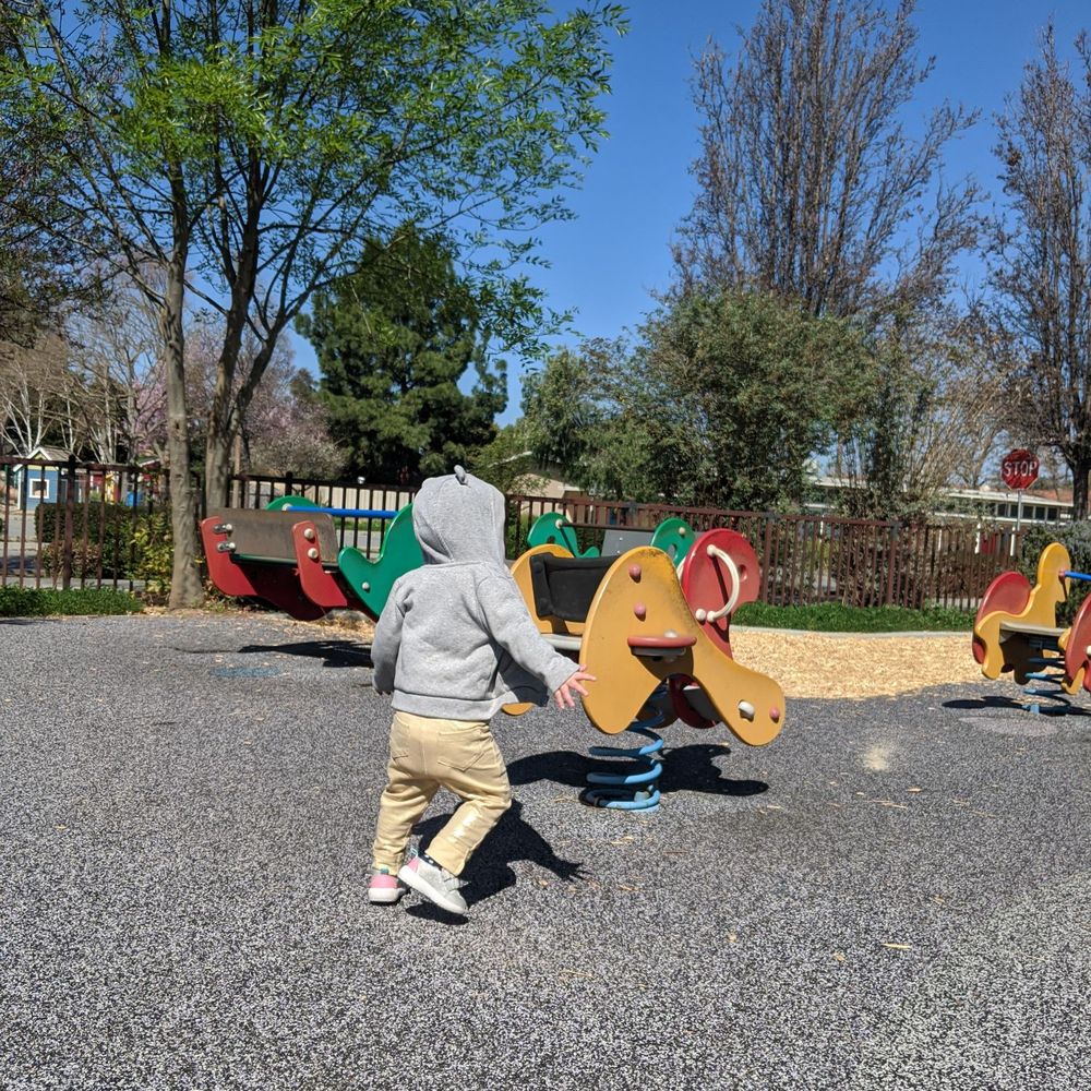 Lincoln Glen Park - Wooden riders and seesaw in the background. Bushes where birds like to hang out. This is prime time entertainment as she LOVES birds. - Parks Near Me - San Jose, California