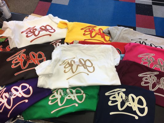 VideosScreen Printing / T-Shirt Printing & Graphic Design Portfolio - We are a creative screen printing studio specializing in custom t-shirts, apparel, and eye-catching graphic design. Whether you’re outfitting a business, promoting an event, or expressing your unique style, our team delivers high-quality prints and inspired designs that look great and last.
Our Services:
Custom screen printing for t-shirts, hoodies, and apparel
Graphic design services (logos, branding, and artwork)
Specialty printing (metallic, puff, and glow-in-the-dark inks)
Bulk orders for businesses, teams, and organizations
Fast turnaround and expert color matching
Why Choose Us:
Combining artistic expertise with state-of-the-art printing technology, we ensure every order meets the highest standards. From concept to final print, we work closely with clients to bring your vision to life—on time and on budget. VideosScreen Printing / T-Shirt Printing & Graphic Design Portfolio - We are a creative screen printing studio specializing in custom t-shirts, apparel, and eye-catching graphic design. Whether you’re outfitting a business, promoting an event, or expressing your unique style, our team delivers high-quality prints and inspired designs that look great and last.
Our Services:
Custom screen printing for t-shirts, hoodies, and apparel
Graphic design services (logos, branding, and artwork)
Specialty printing (metallic, puff, and glow-in-the-dark inks)
Bulk orders for businesses, teams, and organizations
Fast turnaround and expert color matching
Why Choose Us:
Combining artistic expertise with state-of-the-art printing technology, we ensure every order meets the highest standards. From concept to final print, we work closely with clients to bring your vision to life—on time and on budget.