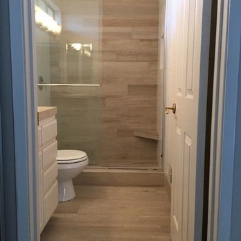 Italian Heritage Tile & Stone - Gust bath with sliding glass doors, corner foot stool, and large porcelain planks set in a staggered pattern. - General Contractors Near Me Italian Heritage Tile & Stone - Gust bath with sliding glass doors, corner foot stool, and large porcelain planks set in a staggered pattern. - General Contractors Near Me