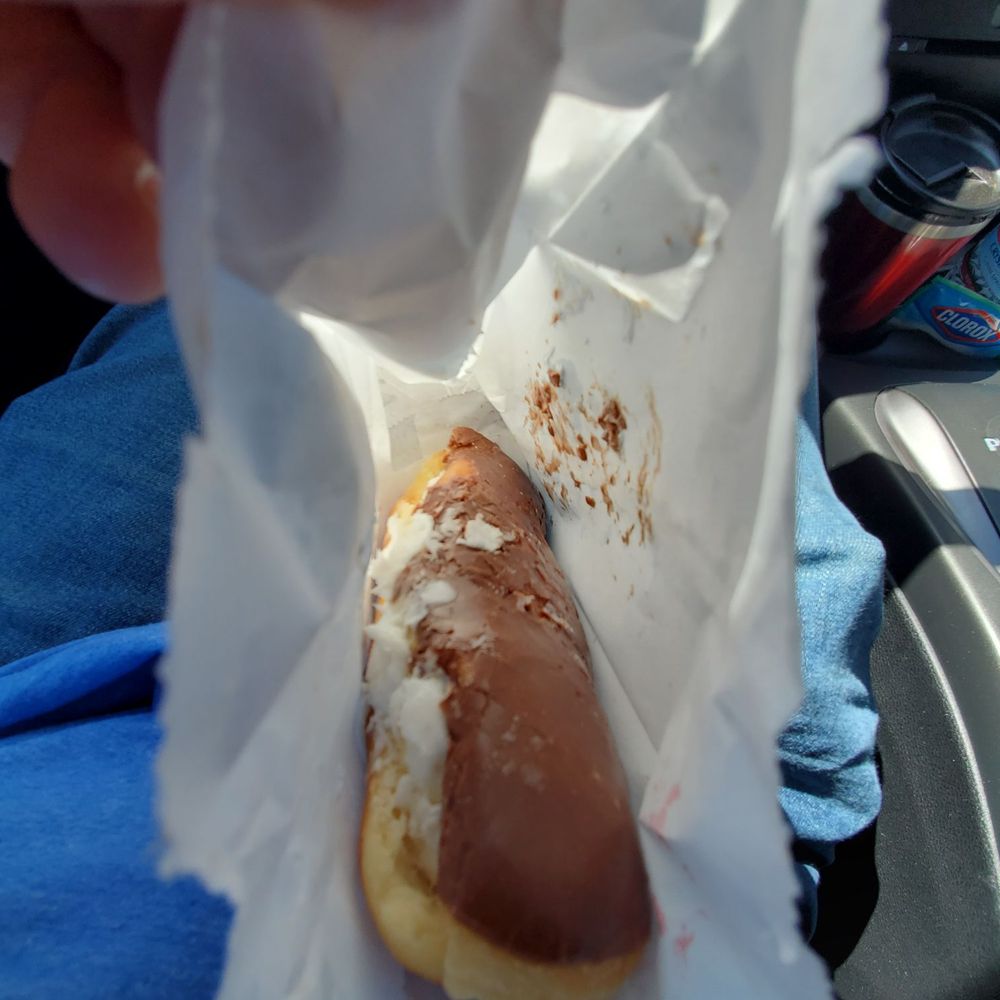 Bakery Donut - a person holding a donut in a wrapper - Donuts Near Me - Robinson, Texas