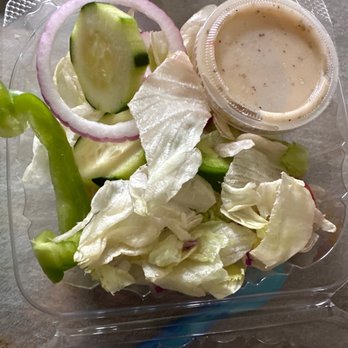 CC Tomatoes - Their side salad - A fresh side salad featuring sliced cucumbers, red onion rings, lettuce, and a small cup of dressing, served in a clear plastic container. - Pizza Near Me - Concord, New Hampshire