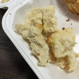Uncooked biscuit dough :( - Pieces of uncooked biscuit dough are inside a white foam food container, with some crumbs and a partially visible fried chicken piece.