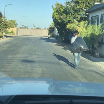 Los Alisos Estates - Husband throwing away the trash at their dumpster, several located in the community. - Apartments Near Me - Westminster, California
