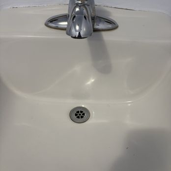 Launderland - She even left the door open for me to leave rushing me , telling me to hurry up - A white ceramic bathroom sink features a chrome faucet mounted on the top center. The sink has a circular metal drain at the bottom with a star-shaped pattern. The background includes a white wall with visible texture and slight imperfections. The image captures the faucet, sink basin, and drain in a straightforward, neutral composition. - Laundromat Near Me - Compton, California