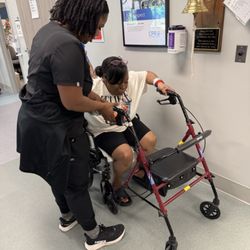Piedmont Encompass Health Rehabilitation Hospital - Autumn my PT helping me stand using the rolling walker. Making sure I use the brakes before standing.