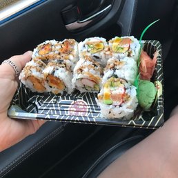 a person holding a tray of sushi