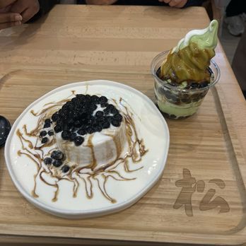 Kyo Matcha - Matcha soft serve with caramel and tapioca pearls in a cup, and a matcha parfait with black tapioca pearls on a wooden tray at Kyo Matcha. - Desserts Near Me - Brookline, Massachusetts