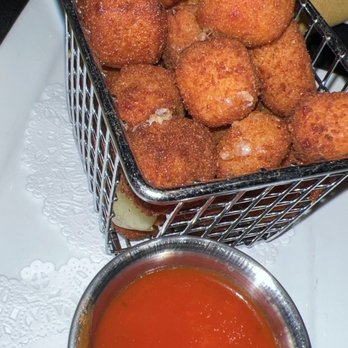 Frix's Fire Grill - Fried croquettes are served in a small metal basket with a side of red dipping sauce in a metal cup, on a white plate. - Latin American Near Me - Chester, Maryland