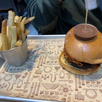 The Chocolatier - Reese's Peanut Butter Crunch Burger (C) Toasted Peanuts, Shallot Jam, Cocoa Spiced Sweet Potato Straws - New American Near Me - Hershey, Pennsylvania The Chocolatier - Reese's Peanut Butter Crunch Burger (C) Toasted Peanuts, Shallot Jam, Cocoa Spiced Sweet Potato Straws - New American Near Me - Hershey, Pennsylvania