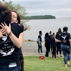 Momentum Education - Service team members embrace after a powerful residential weekend with Leadership Team 158 (pictured in the background)
