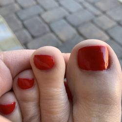 Left big toe with uneven nail, gel polish and cuticle is messy.