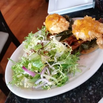 Lucille's - This is the country eggs benedict. Poached eggs on an english muffin w braised greens and bacon.  Mmm mmm good! - New American Near Me - Houston, Texas