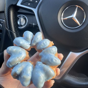 Donut Station - a person holding a donut in front of a steering wheel - Donuts Near Me - Capitola, California