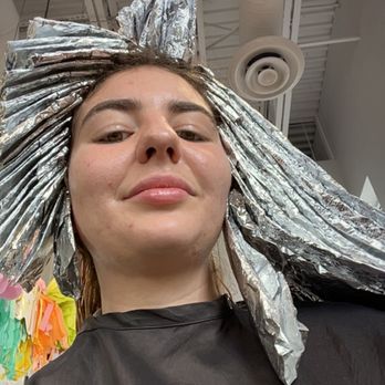 J Salon - Way too many foils! They also let the bleach run down my face and neck quite a bit - A woman with foil in her hair, likely during a hair coloring process, is taking a selfie in a salon setting. The photo is taken from a low angle, showing her face and part of her salon environment. - Hair Salons Near Me - Parker, Colorado