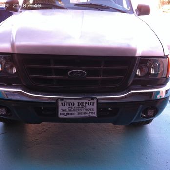 Auto Depot - NEW HEAD LIGHTS LED - A front view of a Ford vehicle is captured, showing the grille, headlights, and bumper. The vehicle is parked on a concrete driveway with grass on the side and other cars visible in the background. The license plate indicates it is from Auto Depot, a dealership in Albuquerque, NM. The photo appears to be taken during daylight hours. - Auto Detailing Near Me - Albuquerque, New Mexico