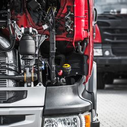 Mega Truck Trailer - Close-up view of a heavy-duty truck engine compartment showing hoses, wiring, suspension components, radiator, and mechanical...