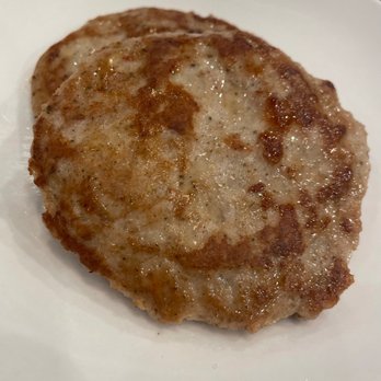 Simone's - Two cooked sausage patties are placed on a white plate, showing a browned, crispy exterior. - Burgers Near Me - Mount Lebanon, Pennsylvania