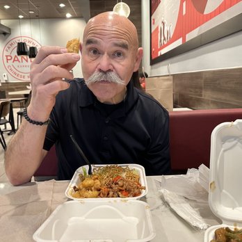 Panda Express - My husband enjoying a spring roll. He loves Panda! He got chow mein with kung pao chicken and the honey shrimp. - Chinese Near Me - Ukiah, California