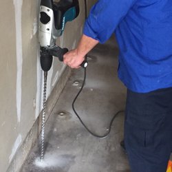 Mills Pest Management - Drilling through the concrete slab in the garage to treat for subterranean termites.
