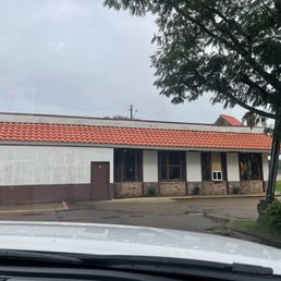 Outside of El Charro - A single-story commercial building with a red tile roof, white walls, and brick accents, situated in a parking lot with a tree in the foreground.