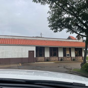 El Charro - Outside of El Charro - A single-story commercial building with a red tile roof, white walls, and brick accents, situated in a parking lot with a tree in the foreground. - Mexican Near Me - Jackson, Mississippi
