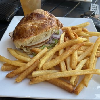 CB Kitchen - Turkey croissant - A croissant sandwich with lettuce, tomato, and possibly turkey, served with a side of French fries on a white square plate. - Burgers Near Me - Willows, California