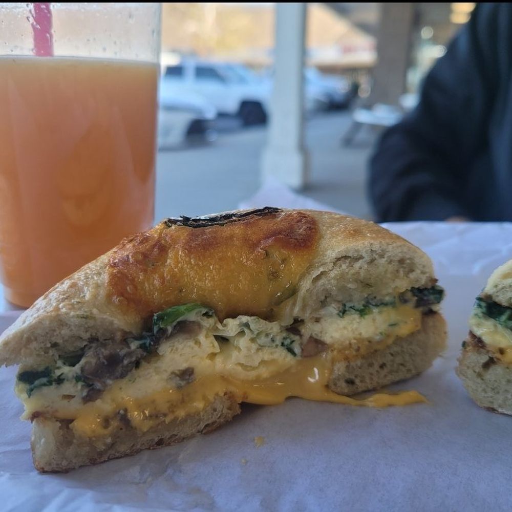 Bagel Junction - Jalapeno breakfast Bagel with egg, cheese, spinach, and bacon.  Fresh squeezed orange juice behind - Coffee & Tea Near Me - Auburn, California