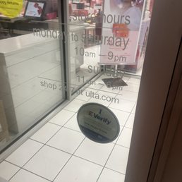 Glass door shows store hours from Monday to Saturday 10 am to 9 pm, Sunday 11 am to 6 pm, and the website ulta.com. An 'iVerify' sticker is on the lower part of the door.